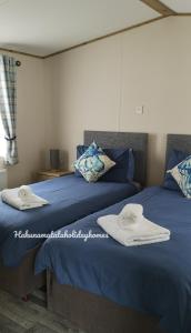 two beds in a room with towels on them at Hakuna Matata Holiday Homes - Accessible Caravan in Newquay