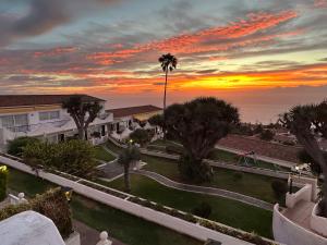 a sunset over a villa with palm trees and the ocean at RedVelvet in Tacoronte