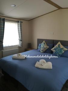 a bedroom with a blue bed with towels on it at Hakuna Matata Holiday Homes - Accessible Caravan in Newquay