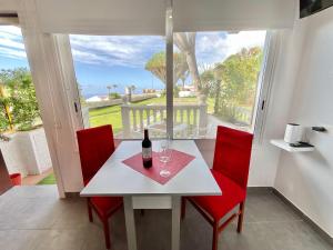 a table with a bottle of wine and two red chairs at RedVelvet in Tacoronte +16 photos