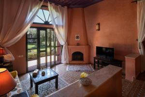 a living room with a fireplace and a large window at Riad Al Riadinou in Aghmat