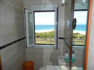 a bathroom with a window with a view of the ocean at Piso en primera línea de playa en Lariño in Lariño +20 photos