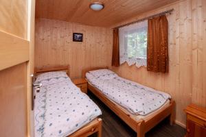 2 Betten in einem kleinen Zimmer mit Fenster in der Unterkunft Domki, pokoje u Małgosi in Sztutowo