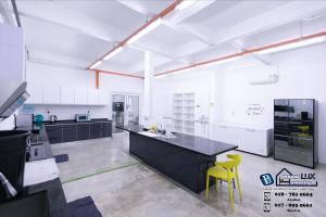 a large kitchen with a black counter and yellow chairs at 15BR SwimmingPool Villa Golf View Snooker BBQ in Bayan Lepas