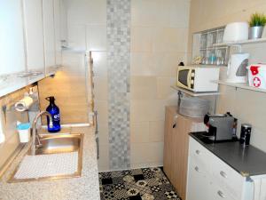 eine kleine Küche mit einer Spüle und einer Mikrowelle in der Unterkunft Arade Rooms in Parchal