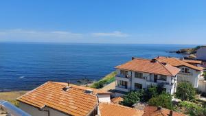 un edificio con techos de tejas naranjas junto al océano en Krai Moreto Guest House en Ahtopol