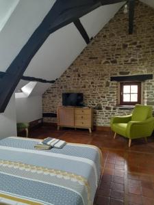 een slaapkamer met een bed en een groene stoel bij La grange de l'épine in Forges-la-Forêt