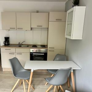 cocina con mesa blanca y 2 sillas en Friesenhof, en Friedrichskoog