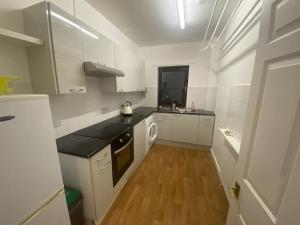 a kitchen with white cabinets and a wooden floor at Steps Away from All the Action in Edinburgh