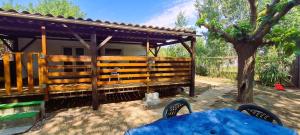 a wooden fence next to a house with a tree at Mobil-home 6 personnes sur terrain 600 m2 in Vias