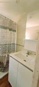 a white bathroom with a sink and a shower at Mobil-home 6 personnes sur terrain 600 m2 in Vias +10 photos