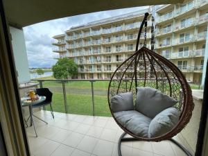 una silla colgante en un balcón con un edificio en Relax and Spa - DeLux Apartman, en Velence