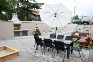 eine Terrasse mit einem Tisch, Stühlen und einem Sonnenschirm in der Unterkunft Commodious house in Rijeka with 5 bedrooms in Rijeka