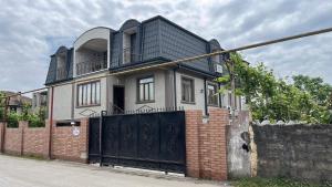 ein Haus mit einem schwarzen Tor und einem Steinzaun in der Unterkunft Guest House OASI in Batumi