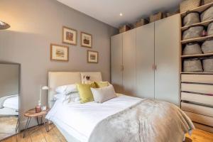 a bedroom with a large white bed and shelves at Stylish 2-Bed House With Office And Private Garden in Windsor