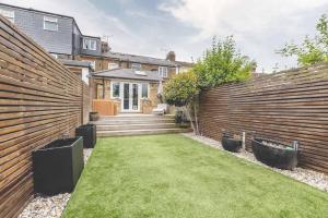 a backyard with a wooden fence and a lawn at Stylish 2-Bed House With Office And Private Garden in Windsor