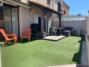 a patio with grass and chairs and a table at Calme, Confortable, Central in Sainte-Maxime