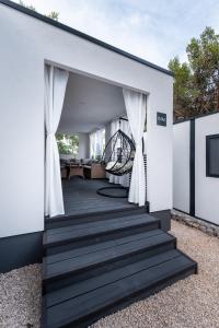 una casa con un ponte nero con pareti bianche di FJAKA luxury mobile home - Oaza Mira Camping Croatia a Drage