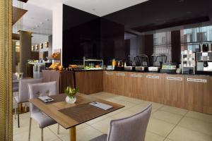 a restaurant with a table and chairs and a kitchen at Residence Inn by Marriott Sarajevo in Sarajevo