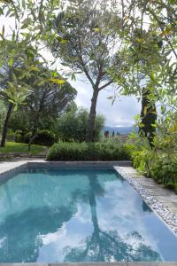 a swimming pool in the middle of a yard with trees at Pieve Aldina Relais & Châteaux in Radda in Chianti