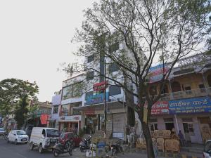ruchliwa ulica miejska z samochodami i drzewem w obiekcie HOTEL SKAGA w mieście Haridwar