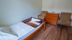 a bedroom with a bed and two chairs and a dresser at Dom Rekolekcyjny CEF Koszalin in Koszalin