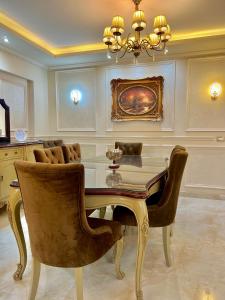een eetkamer met een tafel en stoelen en een kroonluchter bij Ultra Luxury 3BR with Pools ,Sports ,Dining in Gated compound, Close to all sites in Caïro