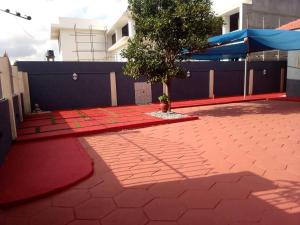 eine rote Backsteinterrasse mit einem Baum und einem blauen Zaun in der Unterkunft 10mins to airport malls wifi no data in Accra