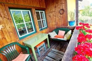 eine Veranda mit einem grünen Tisch, Stühlen und Blumen in der Unterkunft Fallerhaus in Gmünd in Kärnten