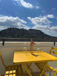 une table jaune avec deux verres à vin sur un balcon dans l'établissement "Lou Mes" Baux-de-provence Balcon, aux Baux-de-Provence