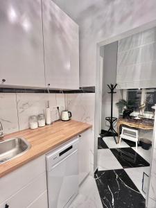 eine Küche mit weißen Schränken und einem schwarz-weißen Boden in der Unterkunft CENTRAL DAINTY in Zagreb