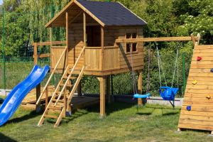 a wooden play house with a slide and swings at Seaside Escape Pet Friendly Apartments Mielenko by Renters in Mielenko