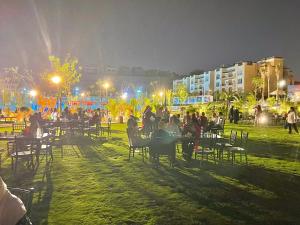 a group of people sitting at tables in a park at night at Ultra Luxury 3BR with Pools ,Sports ,Dining in Gated compound, Close to all sites in Cairo +190 photos