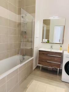een badkamer met een bad, een wastafel en een spiegel bij Cosy chez FIFI in Chessy