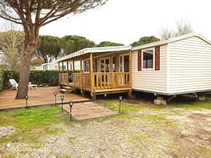 a tiny house with a deck and a tree at MOBILHOME 3 CHBRES 2 SDE 2 WC LV LL TV CLIM TOUT CONFORT in Gastes