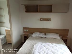 a bedroom with a white bed with a wooden headboard at MOBILHOME 3 CHBRES 2 SDE 2 WC LV LL TV CLIM TOUT CONFORT in Gastes +9 photos