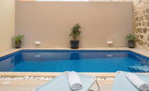 a swimming pool with two lounge chairs next to it at Girgentina Farmhouse in Sannat