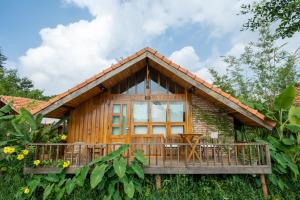 ein Holzhaus mit einer Terrasse in der Unterkunft Mộc An Nhiên Farmstay in Pleiku