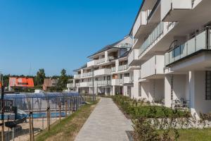 an apartment building with a pathway next to a swimming pool at Apartamenty Mierzeja NCNK Baltic Garden Sztutowo in Sztutowo