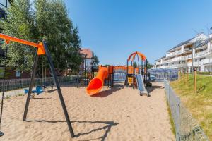 a playground with an orange slide in the sand at Apartamenty Mierzeja NCNK Baltic Garden Sztutowo in Sztutowo