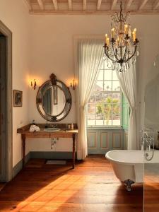een badkamer met een grote spiegel en een bad bij Hotel Emblemático La Casa de los Naranjos in Haría