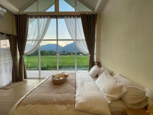 a bedroom with a large bed with a large window at KeawKangNa Farmstay แก้วก๋างนา ฟาร์มสเตย์ in Ban Chong (1)