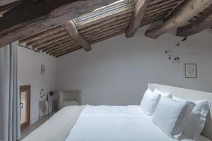 een slaapkamer met een wit bed en houten plafonds bij Pieve Aldina Relais & Châteaux in Radda in Chianti