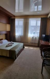Schlafzimmer mit einem Bett, einem Schreibtisch und einem Fenster in der Unterkunft Hotel Salem in Aqtau