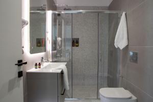 a bathroom with a shower with a toilet and a sink at Achillion Suites in Lefkada Town +42 photos