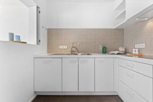 a kitchen with white cabinets and a sink at Seaflow-Holiday appartment with frontal sea view in Oostduinkerke +13 photos