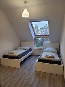 two beds in a room with a window at Apartament Słowińców 61 in Wejherowo