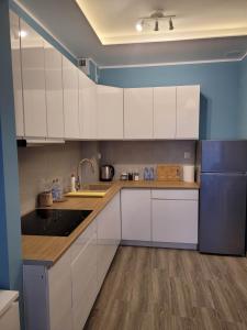 a kitchen with white cabinets and a blue wall at Apartament Słowińców 61 in Wejherowo