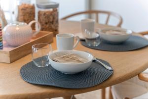 a wooden table with a bowl and plates and glasses at Seaflow-Holiday appartment with frontal sea view in Oostduinkerke