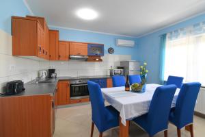 uma cozinha com uma mesa e algumas cadeiras azuis em Apartments Grozic Opatija em Opatija